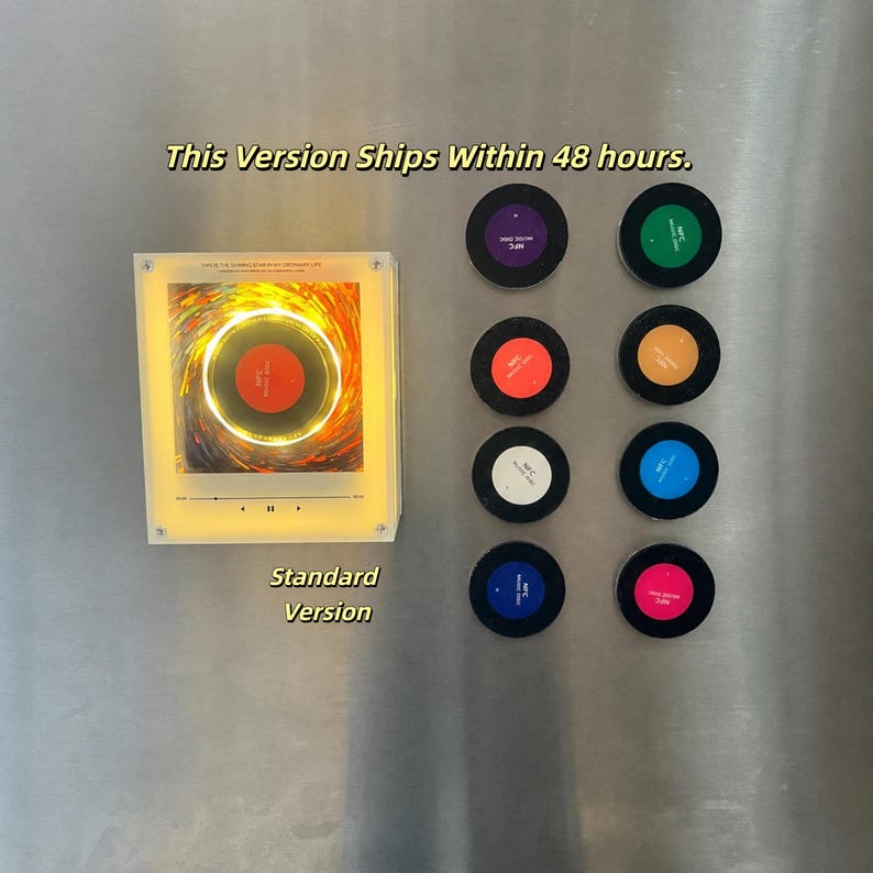 May include: A square, illuminated acrylic display featuring a central circular graphic, accompanied by eight small, circular, multi-colored NFC discs arranged in two vertical columns. Text on the display reads This Is The Darrell Domain Of Ordinary Life.