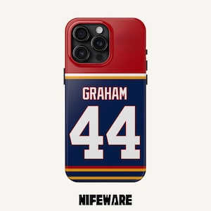 K&ouml;nnte beinhalten: Eine Handyh&uuml;lle mit roter Oberseite und marineblauem Boden. Der marineblaue Bereich zeigt den Namen "GRAHAM" &uuml;ber der wei&szlig;en Nummer "44". Auf der Unterseite der H&uuml;lle steht der Text "NIFEWARE".
