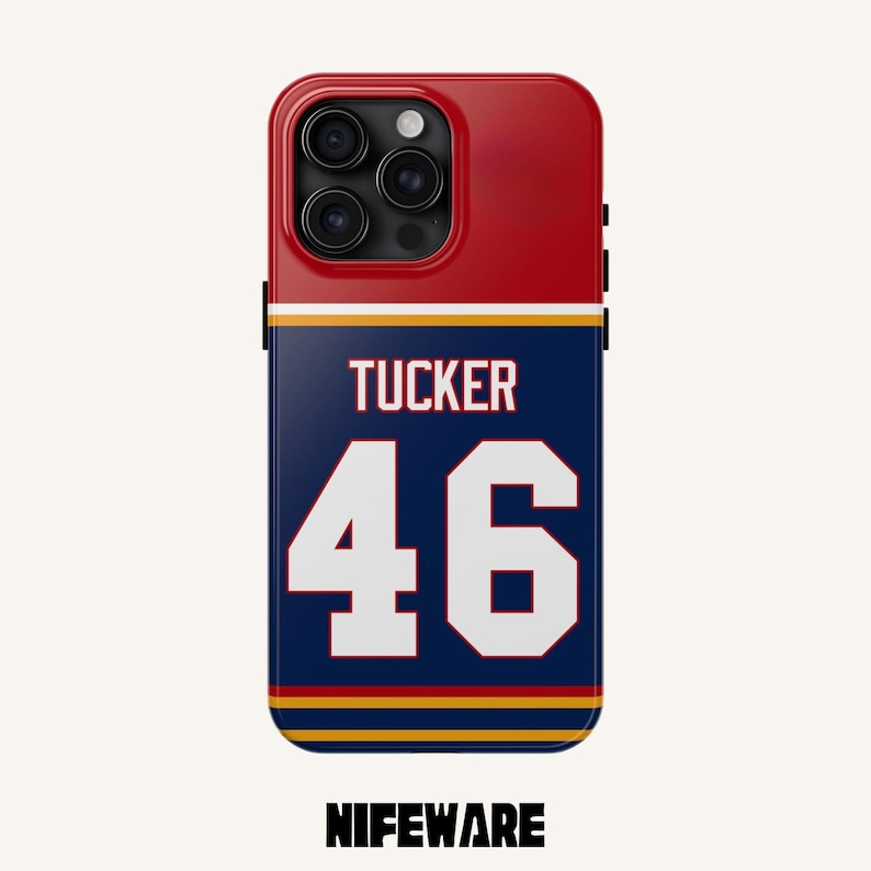 K&ouml;nnte beinhalten: Eine rot-wei&szlig;-blaue Handyh&uuml;lle mit dem Namen "TUCKER" und der Nummer "46" in Wei&szlig;. Die H&uuml;lle hat einen marineblauen Hintergrund mit goldenen und wei&szlig;en Streifen. Der Markenname "NIFEWARE" steht unten.