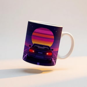 Op de afbeelding: Een witte keramische mok met een grafische illustratie van een donkere sportwagen van achteren gezien, tegen een levendige zonsondergang met horizontale strepen in roze, oranje en paarse tinten, boven een donker rasterpatroon.