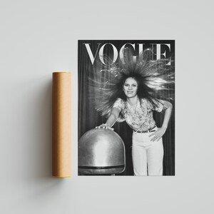 Puede incluir: Una portada de revista Vogue en blanco y negro con una mujer con el pelo peinado hacia arriba. La revista est&aacute; junto a un tubo de p&oacute;ster cil&iacute;ndrico marr&oacute;n. El logotipo de Vogue est&aacute; en la parte superior de la revista.