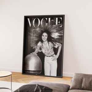 Puede incluir: Portada de la revista Vogue enmarcada en blanco y negro. La imagen muestra a una mujer con el pelo peinado hacia arriba. El logo de Vogue est&aacute; en la parte superior. La mujer lleva una camisa floral y pantalones blancos. El marco est&aacute; apoyado en una pared blanca.