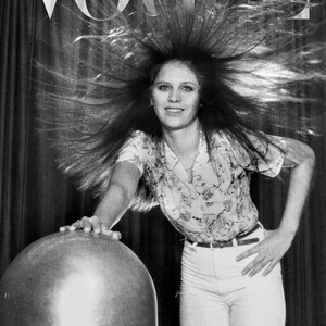 Puede incluir: Portada en blanco y negro de la revista Vogue con una mujer con el pelo erizado. Lleva una camisa con estampado floral, pantalones blancos y un cintur&oacute;n. El logo de Vogue est&aacute; en la parte superior.