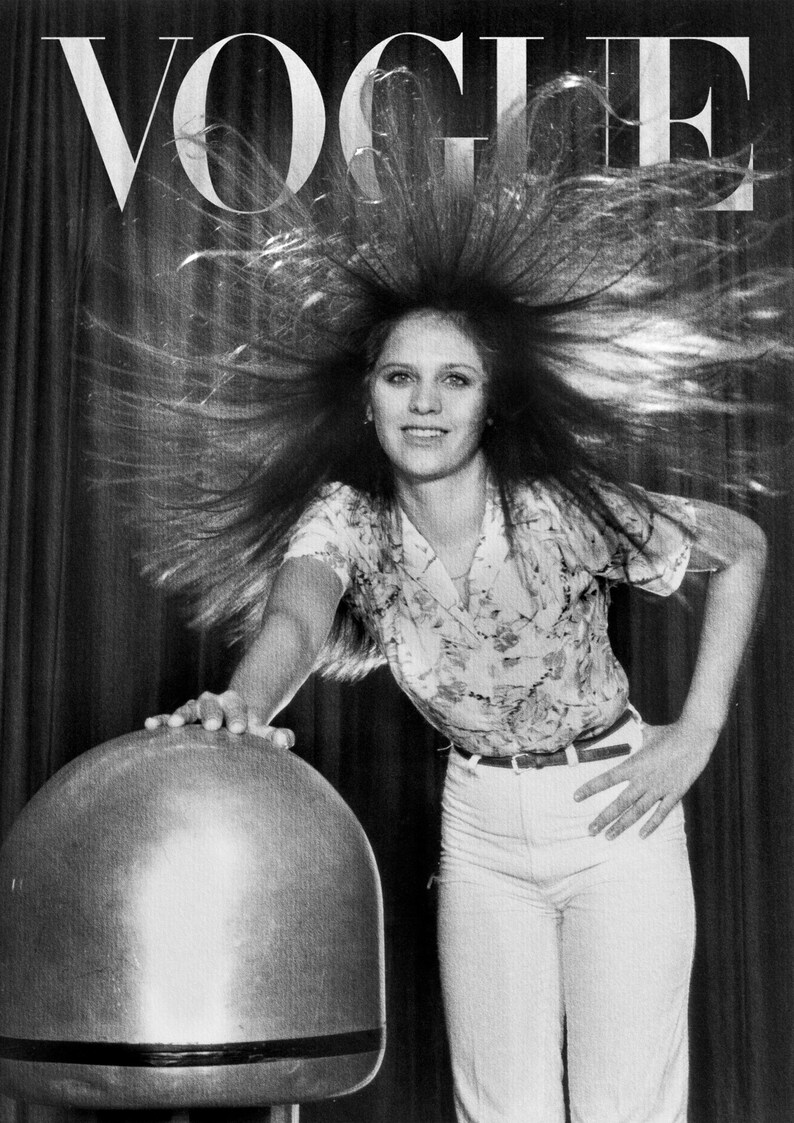 Puede incluir: Portada en blanco y negro de la revista Vogue con una mujer con el pelo erizado. Lleva una camisa con estampado floral, pantalones blancos y un cintur&oacute;n. El logo de Vogue est&aacute; en la parte superior.
