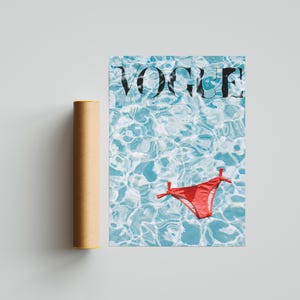 Peut inclure: Une impression de couverture du magazine Vogue avec le logo du magazine et un bikini rouge dans une piscine. Un tube de poster cylindrique marron est &agrave; c&ocirc;t&eacute; de l'impression.