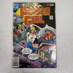Peut inclure: Une bande dessinée vintage Showcase Presents Power Girl, numéro 99, datée d'avril. La couverture présente des illustrations colorées de Power Girl et d'autres personnages, avec des bulles contenant du texte et une scène urbaine sur un écran.