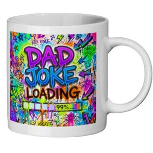 Peut inclure: Mug en céramique blanche avec un motif graffiti coloré. Le mug affiche les mots "DAD JOKE LOADING" en violet et bleu, avec une barre de chargement à 99%. Le fond est orné de divers éléments colorés.