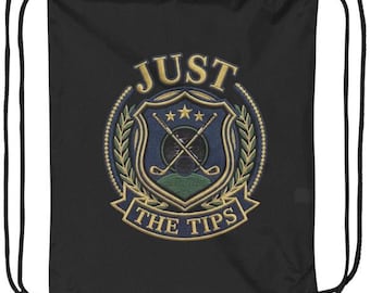 Puede incluir: Una bolsa de cordón negra con un emblema circular bordado. El diseño incluye un escudo azul con palos de golf cruzados, tres estrellas doradas y una base verde, rodeado de hojas de laurel doradas con el texto JUST THE TIPS.