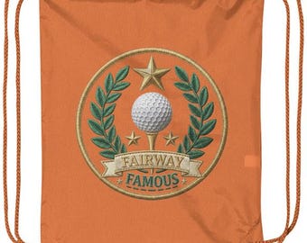 Puede incluir: Una bolsa de cordón naranja con un emblema bordado circular. El emblema muestra una pelota de golf blanca sobre un tee, rodeada de ramas de laurel verdes y tres estrellas doradas. Una cinta debajo dice FAIRWAY FAMOUS en letras verdes.