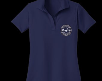 Puede incluir: Un polo de manga corta en color azul marino con cuello y tapeta en forma de V. En el pecho izquierdo, hay un gráfico circular con un icono de palo de golf y el texto "Definitely Maybe MY LAST ROUND" en letras blancas y doradas.