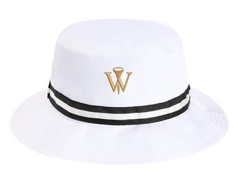 Puede incluir: Un sombrero de pescador blanco liso con un logotipo de la letra W bordado en dorado en la parte delantera. El sombrero presenta una cinta horizontal a rayas negras y blancas que rodea la base de la copa, creando un contraste con el tejido blanco.