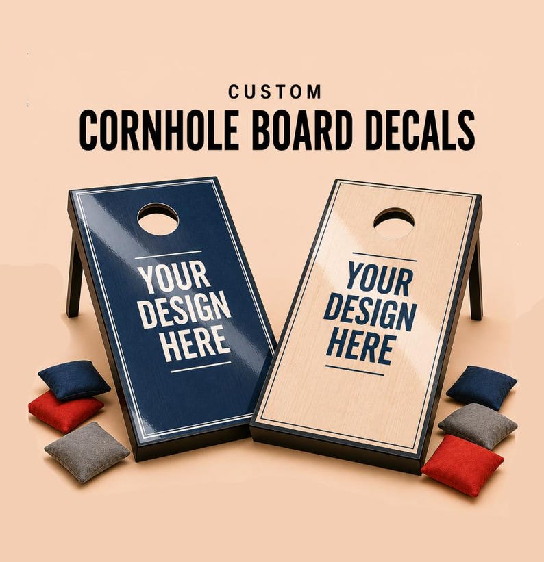 May include: Two cornhole boards with black frames and glossy surfaces, one dark blue and one light wood-grain, both featuring the text "YOUR DESIGN HERE" in dark blue. Includes six bean bags in red, blue, and gray, with "CUSTOM CORNHOLE BOARD DECALS" text.