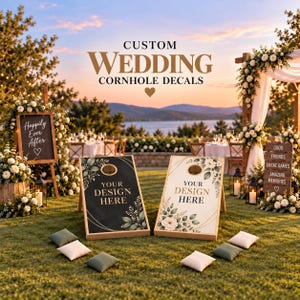 May include: Two wooden cornhole boards featuring custom decals with floral accents and gold geometric lines. One board is black, the other is white, both displaying the text 'YOUR DESIGN HERE'. Four small square bean bags are placed on the grass.