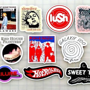 Può includere: Una collezione di adesivi in vinile con vari loghi di band e copertine di album. I design includono "Drop Nineteens", "Slowdive", "Lush", "Red House Painters", "My Bloody Valentine", "Galaxie 500", "Failure", "HotrobRite" e "Sweet Trip".