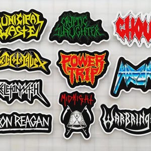 May include: A collection of die-cut stickers featuring various heavy metal band logos. The stickers display bold text in vibrant colors like yellow, red, and blue, with black and white outlines. Bands include Municipal Waste, Power Trip, and Iron Reagan.