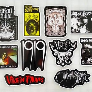 May include: A collection of ten rectangular and die-cut stickers featuring various band logos and album art. Designs include text such as Hlidar Mikla, Cemetery, Rasputina, Super Heroines, Rosegarden Funeral Party, 1919, Mephisto Walz, Boy Harsher, Virgin Prunes, and Cinema Strange.
