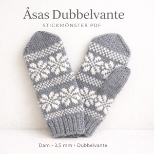 May include: A pair of grey and white knitted mittens with a snowflake design. The mittens feature a ribbed cuff and are labelled "Åsas Dubbelvante" and "STICKMÖNSTER PDF". The text "Dam · 3,5 mm · Dubbelvante" is also visible.