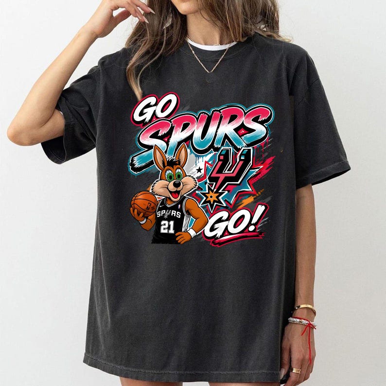 以下が含まれることがあります： バスケットボールを持った漫画のウサギが描かれた黒いTシャツ。背番号「21」のユニフォームを着ています。「GO SPURS GO！」の文字がカラフルなデザインでプリントされています。楽しくスポーティーなグラフィックTシャツです。