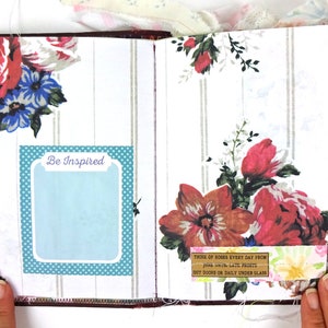 May include: An open journal with a floral design and a blue and white polka dot border. The journal has a quote on the right page that reads "Think of roses every day from June until late frosts out doors or daily under glass". The left page has a blue and white polka dot border with a white rectangle that says "Be Inspired".