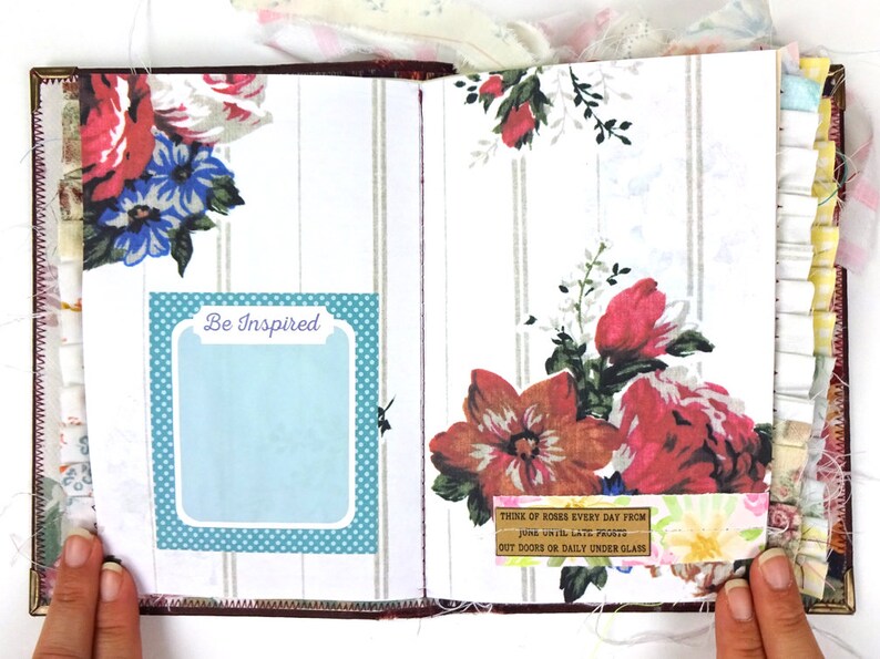 May include: An open journal with a floral design and a blue and white polka dot border. The journal has a quote on the right page that reads "Think of roses every day from June until late frosts out doors or daily under glass". The left page has a blue and white polka dot border with a white rectangle that says "Be Inspired".