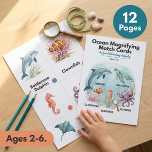 May include: Ocean Magnifying Match Cards with illustrations of sea creatures, including a dolphin, clownfish, and sea turtle. The set includes 12 pages and is designed for ages 2-6. A magnifying glass and pencils are also visible.