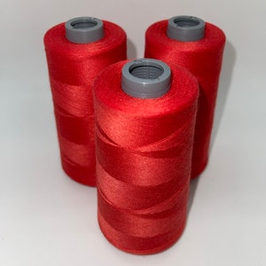 May include: Three spools of red thread, each with a gray plastic top.