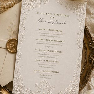Pode incluir: Cartão elegante com cronograma de casamento com detalhes florais em relevo. O cartão apresenta os nomes "Olivia e Alexander" e um cronograma que inclui a chegada dos convidados, palavras de abertura, jantar, corte do bolo e palavras de encerramento.
