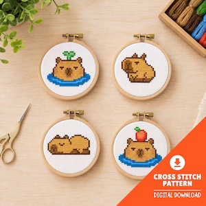 May include: Four cross-stitch patterns of capybaras in wooden hoops. The capybaras are in various poses, some in water, and one with a sprout on its head. The text "CROSS STITCH PATTERN DIGITAL DOWNLOAD" is in the lower right corner.