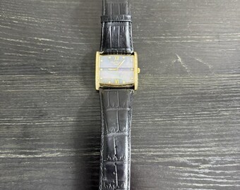 Reloj Swiss Legend con bisel de diamantes, tono oro y negro, correa de cuero y nácar.