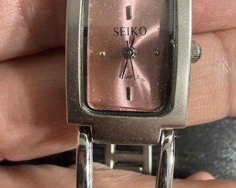 Reloj Seiko de cuarzo vintage con esfera rosa en funcionamiento.