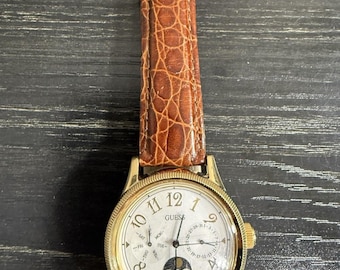 Reloj Guess vintage japonés con movimiento, multifunción, estilo fase lunar, tono dorado, en funcionamiento.