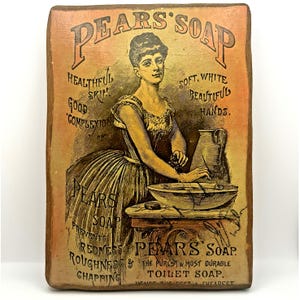 May include: A rectangular wooden plaque featuring a vintage advertisement for Pears' Soap. The print depicts a person washing hands in a basin with text including "Pears' Soap," "Healthful Skin," "Soft, White Beautiful Hands," and "The Purest & Most Durable Toilet Soap."