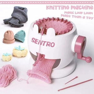 Può includere: Una macchina per maglieria Sentro bianca e rosa con manovella e letto ad aghi circolare. Include filato rosa, due ferri da maglia ed esempi di articoli lavorati a maglia: una sciarpa grigia, due piccoli cappelli e due oggetti a forma di zucca.