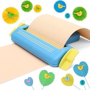 Op de afbeelding: Een lichtblauw papier-crimper gereedschap met gele handgrepen aan de zijkanten, dat een vel beige papier door de rollen voert om een gegolfde textuur te creëren. Versierd met diverse kleine, kleurrijke papieren waaiers met vogelvormen.