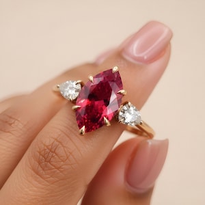 Puede incluir: Una taza de cerámica blanca con asa negra y el texto "But First, Coffee" en negrita negra. La taza se encuentra sobre un fondo borroso, sugiriendo un ambiente acogedor.