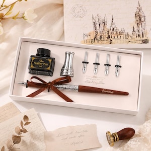 Peut inclure: Un ensemble de calligraphie dans une bo&icirc;te blanche comprenant un stylo en bois marron grav&eacute; du nom Emma, un flacon d'encre noire &eacute;tiquet&eacute; The Feather Pen, un porte-plume argent&eacute; et quatre plumes argent&eacute;es. Un sceau &agrave; cire est inclus.