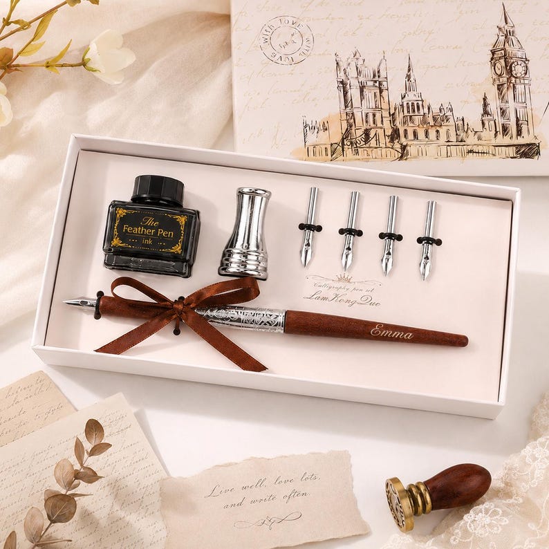 Peut inclure: Un ensemble de calligraphie dans une bo&icirc;te blanche comprenant un stylo en bois marron grav&eacute; du nom Emma, un flacon d'encre noire &eacute;tiquet&eacute; The Feather Pen, un porte-plume argent&eacute; et quatre plumes argent&eacute;es. Un sceau &agrave; cire est inclus.