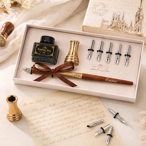 Peut inclure: Un ensemble de calligraphie dans une bo&icirc;te blanche comprenant un stylo en bois avec un ruban marron, un flacon d'encre noire &eacute;tiquet&eacute; The Feather Pen, un porte-stylo dor&eacute; et cinq plumes argent&eacute;es. Le stylo porte le nom Emma. Lettre et plumes incluses.