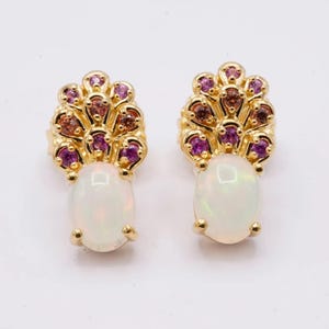 May include: A pair of gold earrings with a white opal gemstone and a cluster of pink and brown gemstones.