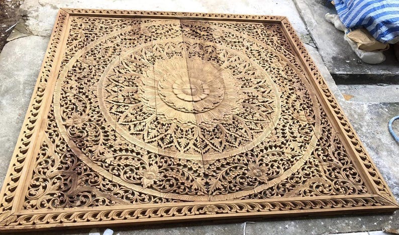 Puede incluir: Panel de madera tallada, grande y cuadrado, con intrincados detalles. Presenta un dise&ntilde;o floral central rodeado de patrones detallados y un borde decorativo. La madera tiene un tono c&aacute;lido y natural, mostrando la artesan&iacute;a. Adecuado para decoraci&oacute;n mural.