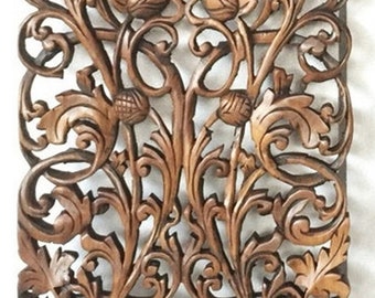 May include: Intricately carved wooden wall decor with a floral design. The wood is a rich brown color and the carving is very detailed. The design is symmetrical and features a central motif of a flower.