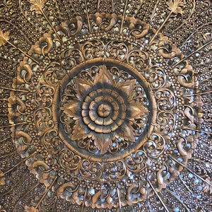 Puede incluir: Panel de madera tallado a mano con un motivo floral central y patrones intrincados. El panel es de color marr&oacute;n c&aacute;lido, con tallas en relieve detalladas de flores y motivos arremolinados. El dise&ntilde;o general es sim&eacute;trico y decorativo.