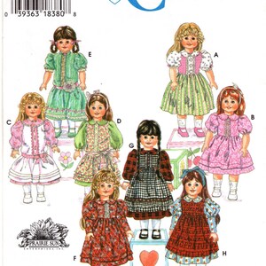 May include: A Simplicity Crafts sewing pattern envelope, number 9856, featuring illustrations of eight dolls wearing various dresses. The designs include floral, plaid, and alphabet prints with puff sleeves, collars, and ribbons. Text includes Simplicity Crafts.