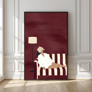 Könnte beinhalten: Ein gerahmter Wandkunstdruck, der eine Person in einem weißen Hemd zeigt, die auf einem gestreiften Sofa liegt, wobei ein Buch das Gesicht bedeckt. Eine Stehlampe steht neben dem Sofa vor einem tiefburgunderroten Hintergrund mit Pinselstrichen.