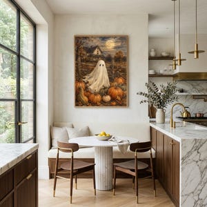 May include: A framed wall art print depicting a white ghost standing in a pumpkin patch at night with a full moon and a house in the background. The scene features orange pumpkins, autumn foliage, and dark trees under a moonlit sky.
