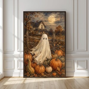 May include: A framed wall art print depicting a white ghost standing in a pumpkin patch at night. In the background, a two-story house sits under a full moon. The scene features orange pumpkins, green gourds, and a wooden fence under a dark sky.