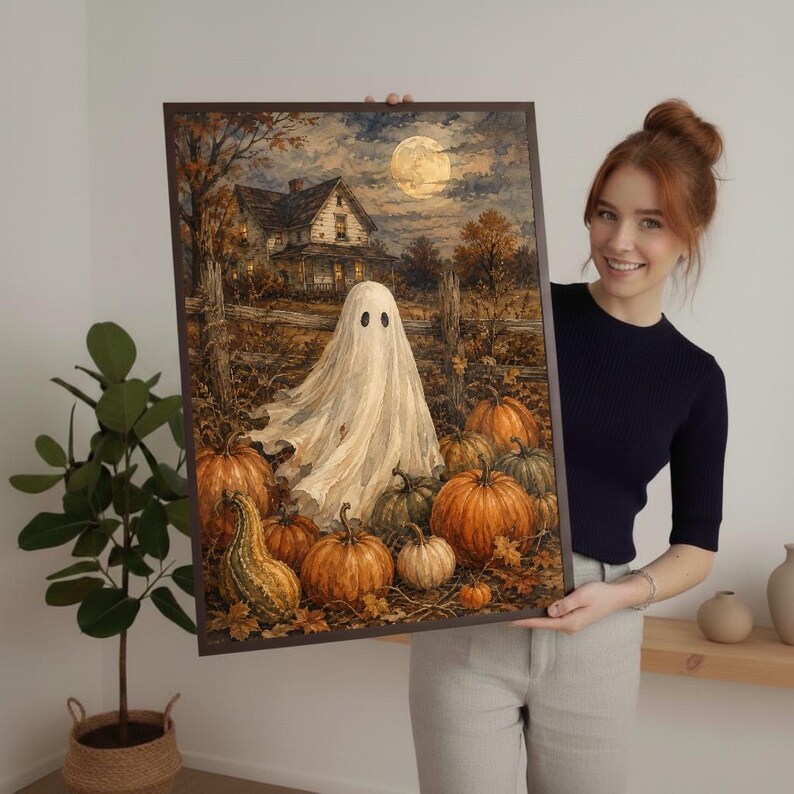 May include: A framed rectangular wall art print featuring a white ghost standing in a pumpkin patch in front of a house under a full moon. The scene includes orange pumpkins, a wooden fence, and autumn trees in a dark, atmospheric color palette.