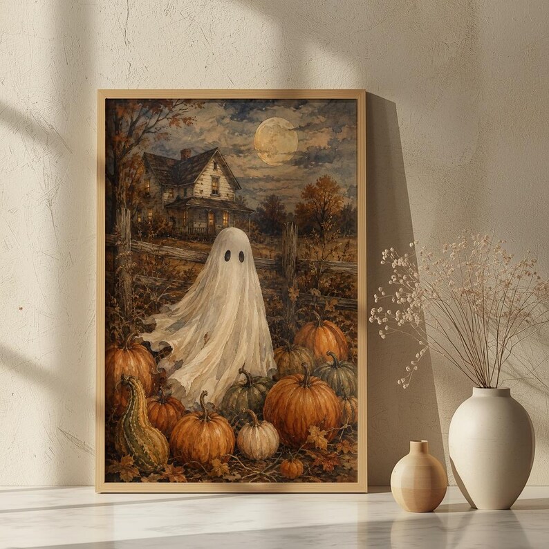 May include: A framed wall art print depicting a white ghost standing in a pumpkin patch at night. The scene features a dark house in the background, a full moon in the sky, and numerous orange pumpkins of various sizes scattered across the ground.