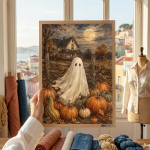 May include: A framed art print depicting a white ghost standing in a pumpkin patch in front of a house under a full moon. The scene features orange pumpkins, a wooden fence, and autumn trees in a dark, atmospheric setting with a light-colored sky.