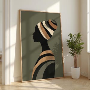 Peut inclure: Une impression d'art encadrée représentant une silhouette d'une personne avec un turban et des vêtements rayés. L'œuvre d'art est principalement noire, avec des rayures beiges, marron et grises sur un fond vert. Le cadre est en bois clair.